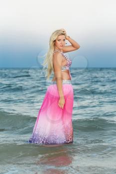 Attractive young blonde in pink dress posing in the water