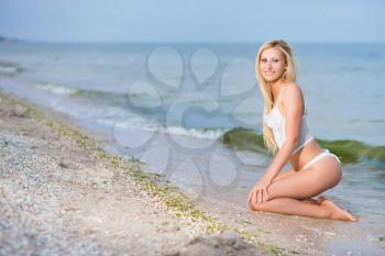 Sexy blond woman in lingerie posing on the beach