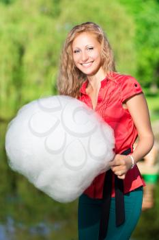 Young smiling blond woman holding a cotton candy