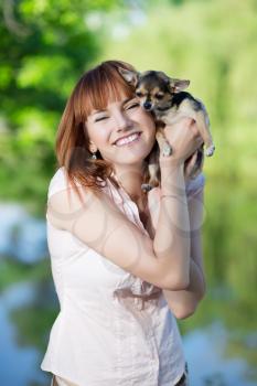 Young smiling red-haired woman posing with a funny little dog