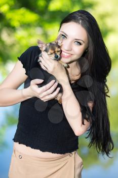 Young cheerful brunette posing with a funny little dog