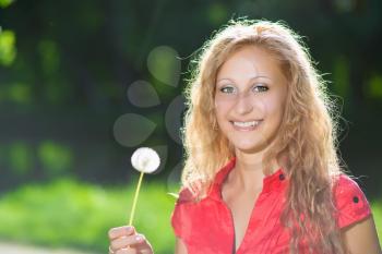 Portrait of pretty cheerful blond woman posing with a dandelion
