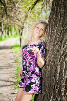Sexy blond woman posing in the park near a tree
