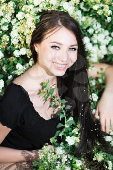 Young cheerful brunette posing in the flowering bushes
