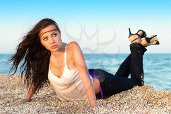 Sexy young brunette posing in wet clothes on the beach