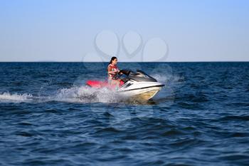 Young brunette in life jacket riding on a jetski
