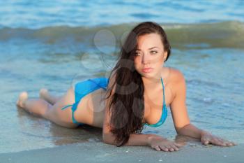 Sexy young brunette in blue swimsuit lying on the beach