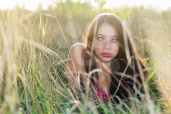 Frightened young brunette hiding in the dry grass