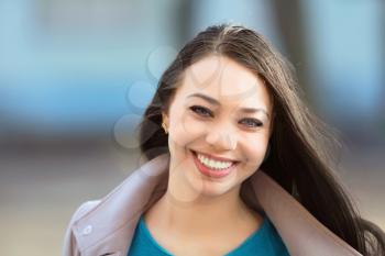 Portrait of young cheerful brunette posing outdoors
