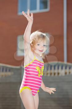 Portrait of funny little blond girl in swimsuit