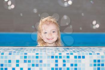 Happy little blond girl posing in water pool