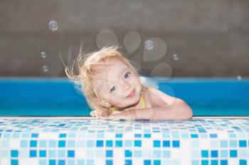 Cute little blond girl posing in water pool