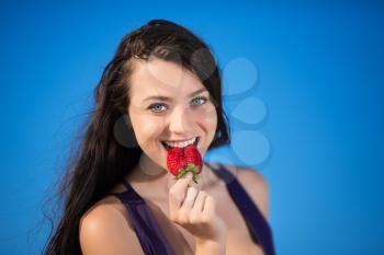 Portrait of playful young brunette posing with strawberry