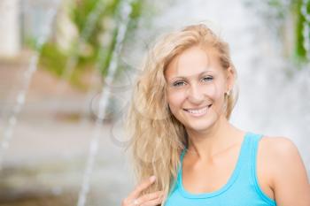 Portrait of smiling blond woman posing near the fountain