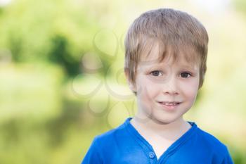 Portrait of little boy posing outdoors in blue shirt