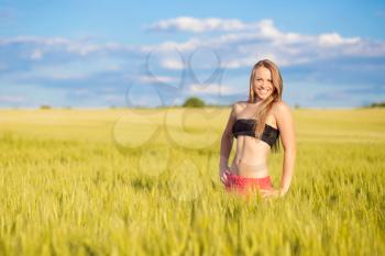 Cheerful young blond woman posing on the field