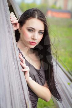 Portrait of pretty brunette posing behind the wooden fence
