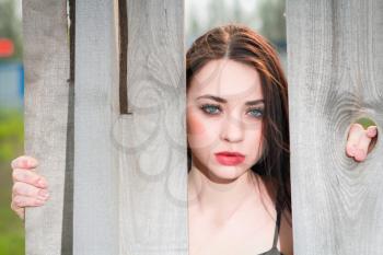 Portrait of young pensive woman behind the wooden fence