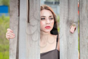 Portrait of pretty thoughtful woman posing behind the wooden fence