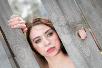 Portrait of thoughtful brunette posing behind the wooden fence