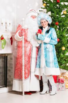 Snow maiden and santa claus posing near christmas fir