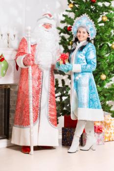 Snow maiden and santa claus posing near christmas tree