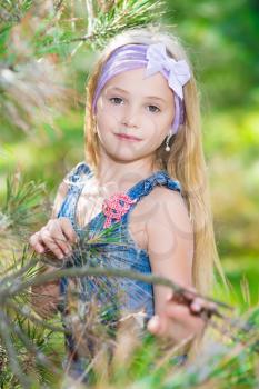Portrait of blond girl posing in pine branches