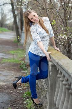 Joyful pretty blonde posing in white shirt, blue pants and black shoes