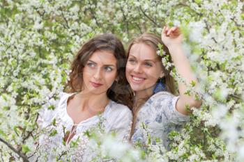 Pretty young caucasian women posing in blooming garden