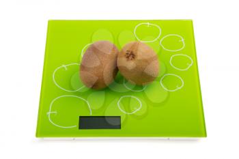 Two ripe kiwi fruit on square kitchen scales. Isolated