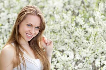 Young smiling woman with beautiful hair in blooming garden
