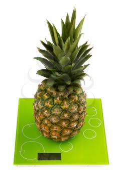 Close-up of sweet pineapple on square kitchen scales. Isolated