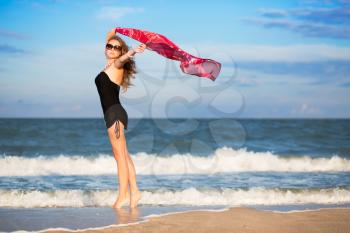 Pretty slim woman with pink pareo posing on the beach