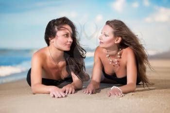 Two attractive women lying on the beach