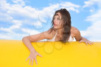 Young sexy brunette posing on the edge of a yellow pool