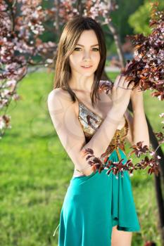 Attractive young caucasian lady touching leaves of the tree
