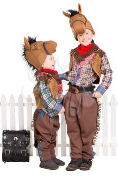 Two boys wearing horse costumes and posing near the fence. Isolated on white