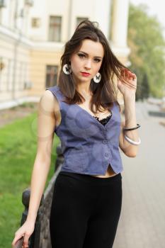 Pretty young woman posing outdoors in grey vest