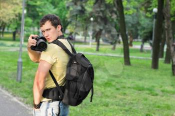 Young handsome man with serious look making photos in the park