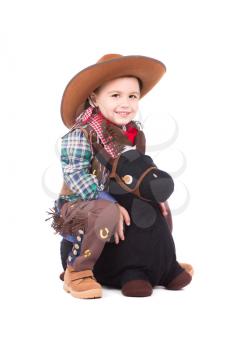 Smiling little cowboy posing on the toy horse. Isolated