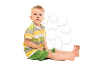 Little blond boy in green short sitting. Isolated on white