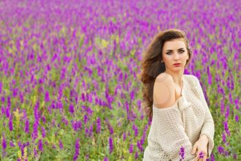 Young sexy curly brunette posing in a flowering field