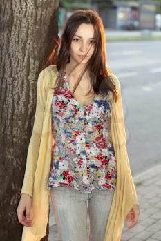 Young thoughtful lady in flowered blouse posing near the carriageway
