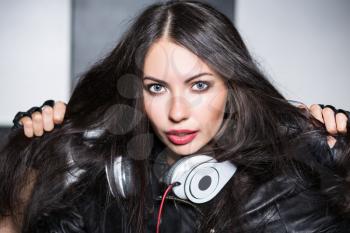 Portrait of playful young woman with headphones posing in the studio