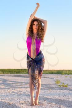 Attractive curly young brunette posing in fashionable beachwear