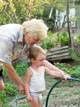 Grandmother and grandson in the garden watering