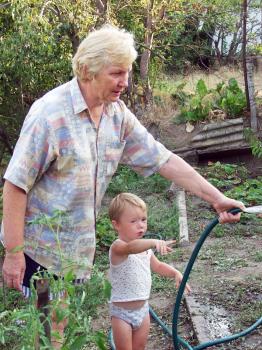 Grandmother and grandson in the garden watering