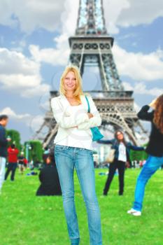 Girl with another tourists is posing against  backdrop of Eiffel Tower
