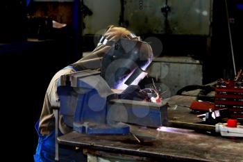 Welder working in production workshop on a workbench