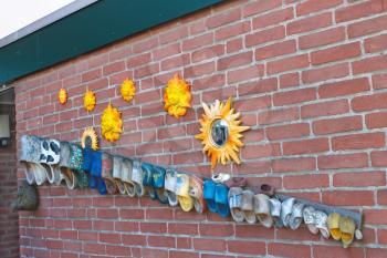 Wall dutch house  decorated old shoes and sun. Netherlands